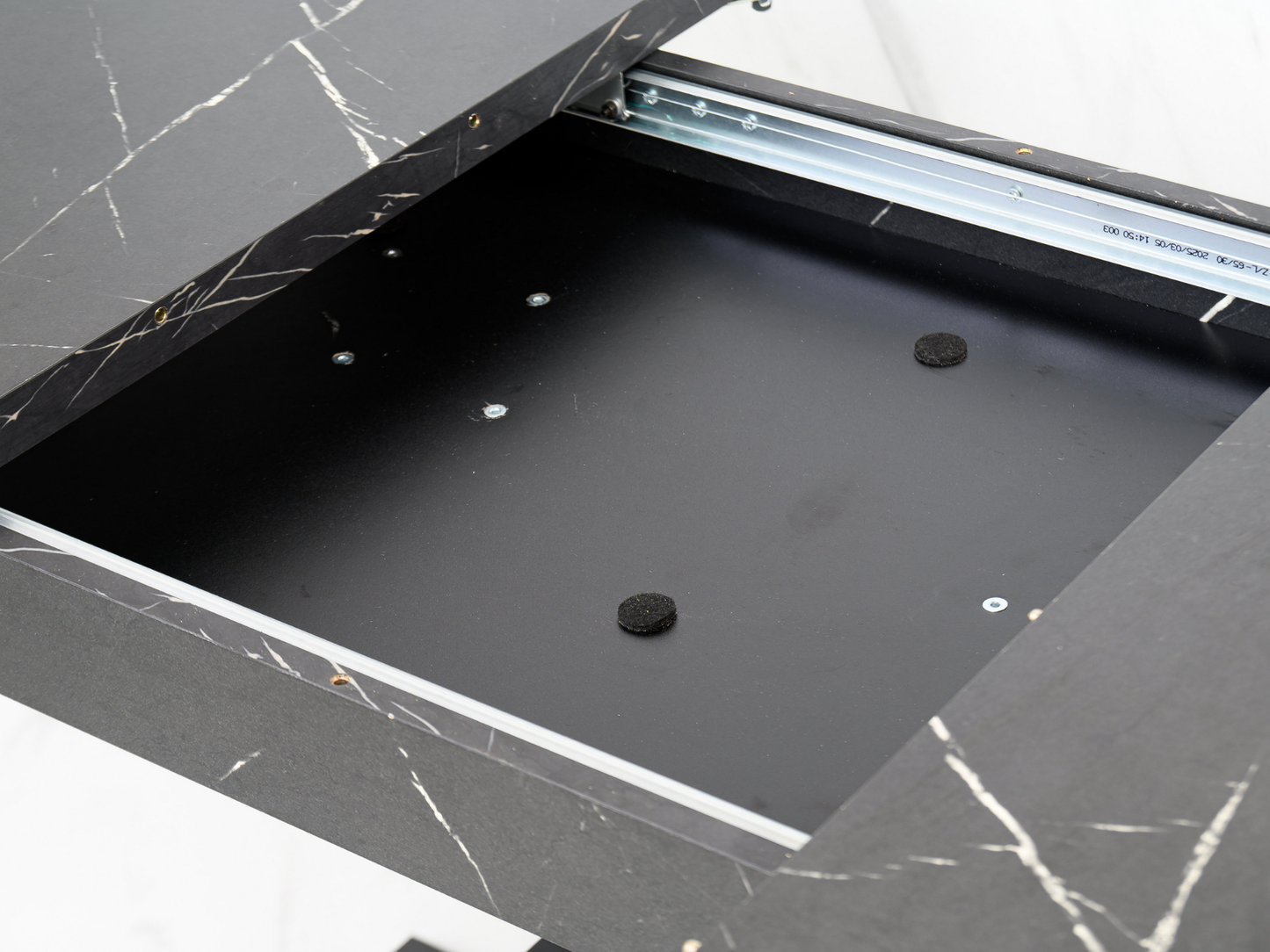 Detail of the extending table mechanism hidden beneath the black marble effect top