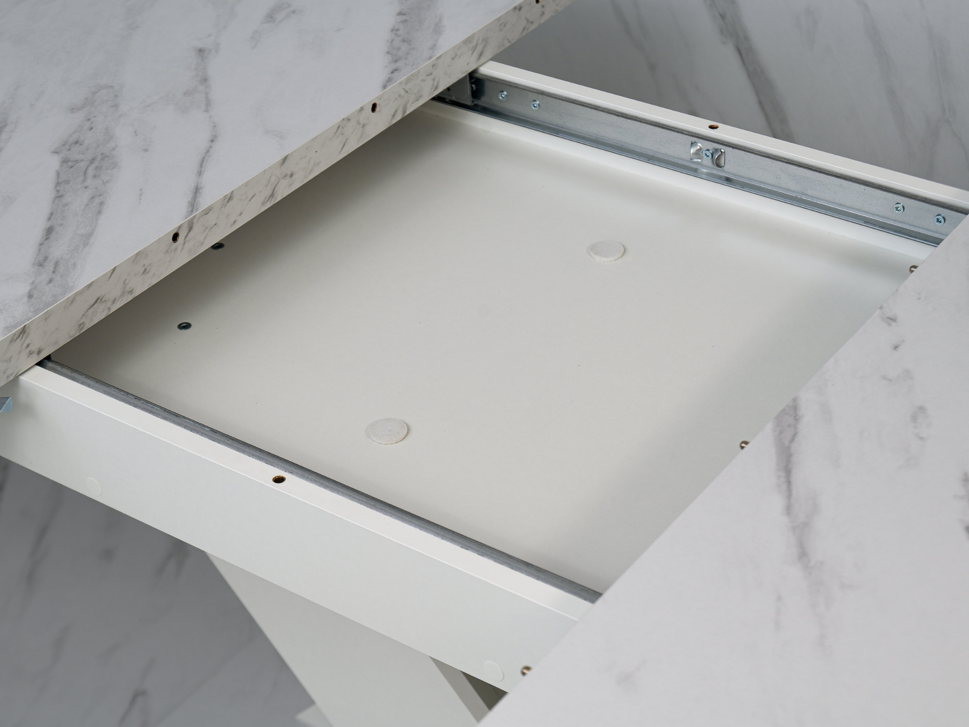 Detail of the extending table system concealed beneath the White Bianco marble effect top