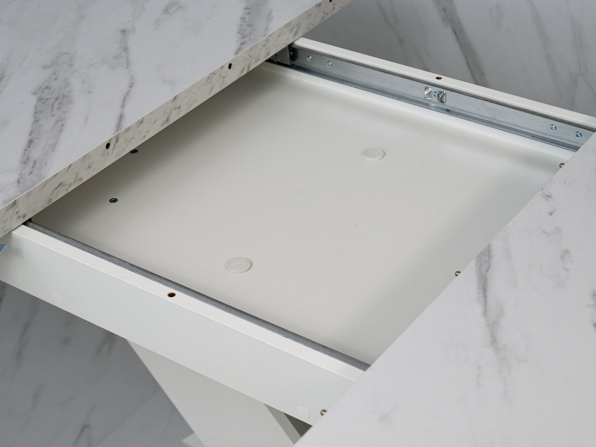 Detail of the extending table system concealed beneath the White Bianco marble effect top