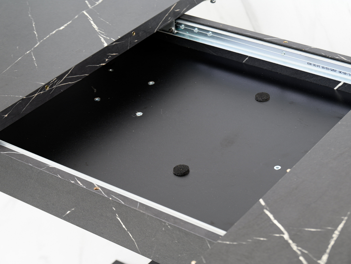 Detail of the extension system beneath the black marble effect top of the WOOD MINI table