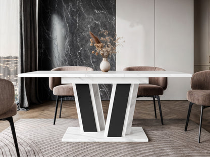 Elegant Muss extending dining table in a living room with fireplace, white marble effect tabletop, black V-shaped pedestal base, upholstered dining chairs, suitable for comfortable seating for 4–6 people.