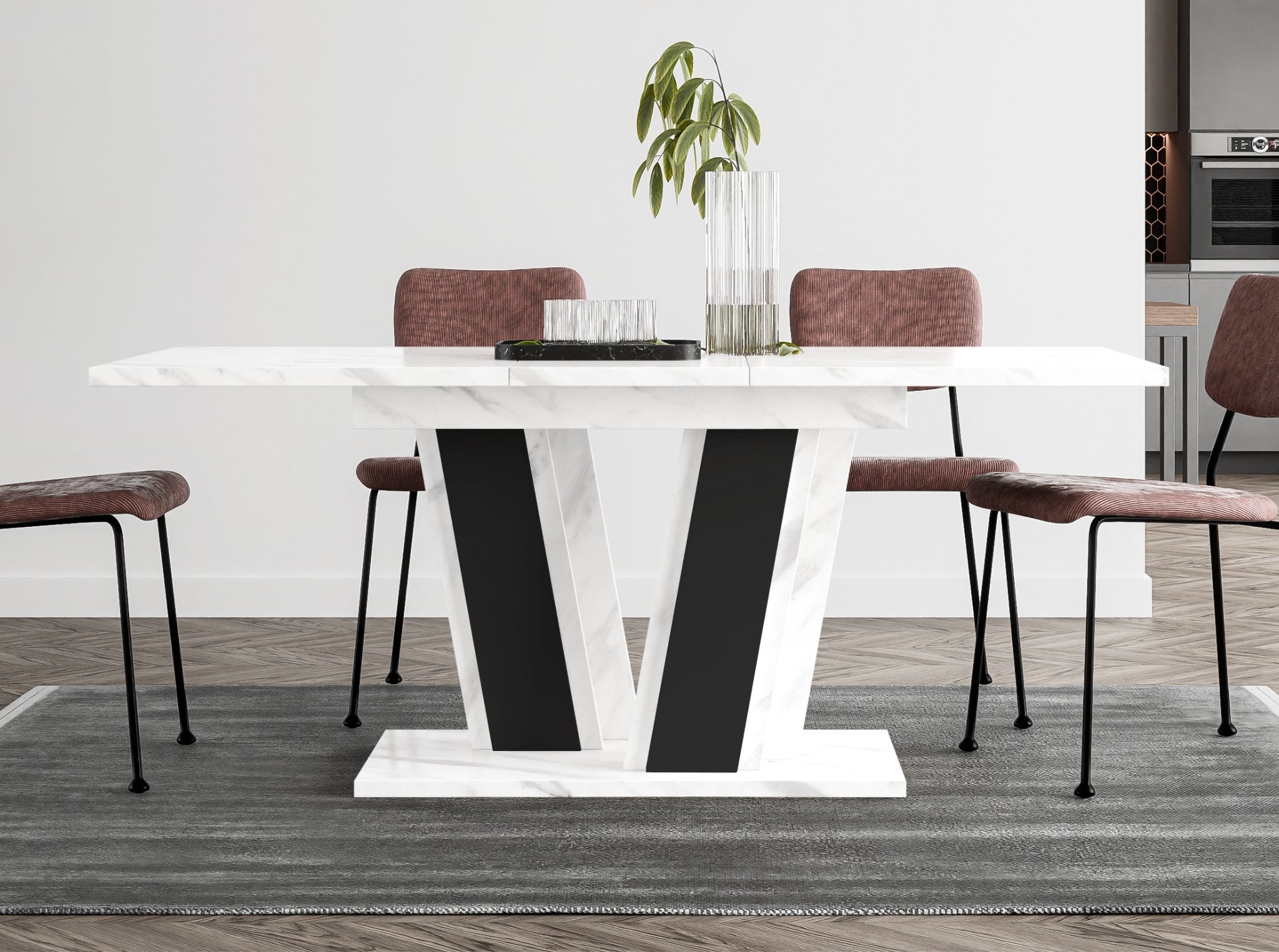 Muss extending dining table placed in a modern dining room interior, white marble effect tabletop, black base, positioned on a rug with upholstered dining chairs around the table.