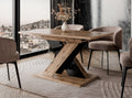TOXX extending dining table with a wotan oak effect finish placed in a modern dining room setting, black gloss X-shaped pedestal base, upholstered dining chairs arranged around the table on a rug.